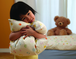 Kind mit Kissen der Kindersatinbettwäsche Kritzelkreise aus Bio-Baumwolle von Cotonea