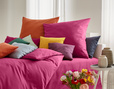 Bett mit Bio Satin Bettwäsche Classic in Sangria und Orange mit bunten Kissen von Cotonea