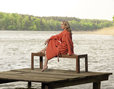 Frau trägt Koralle-Roten Bio Waffelpikee-Bademantel am See und sitzt auf einem Steg