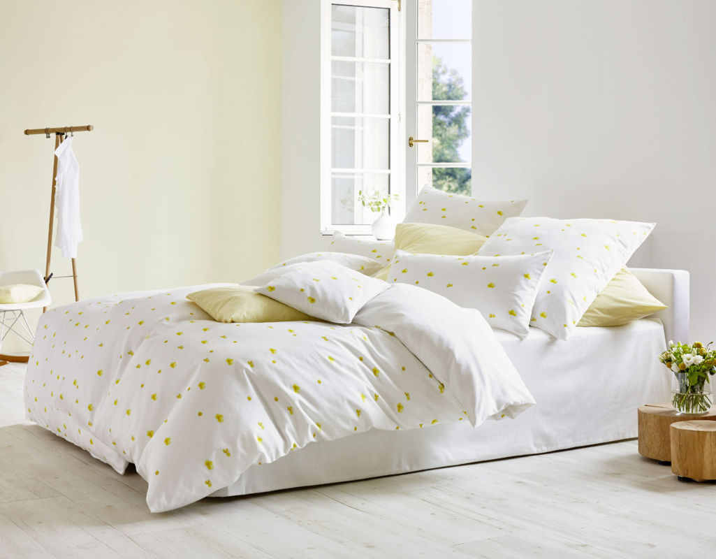 Bio-Bettwäsche mit gelben Butterblumen auf Weiß im Schlafzimmer